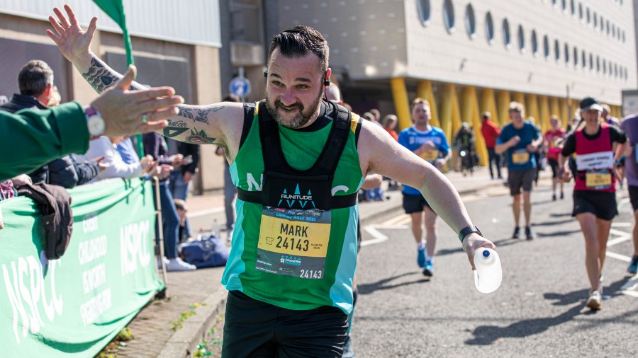 Cardiff Half runner in NSPCC vest, slapping palms with someone in the crowd