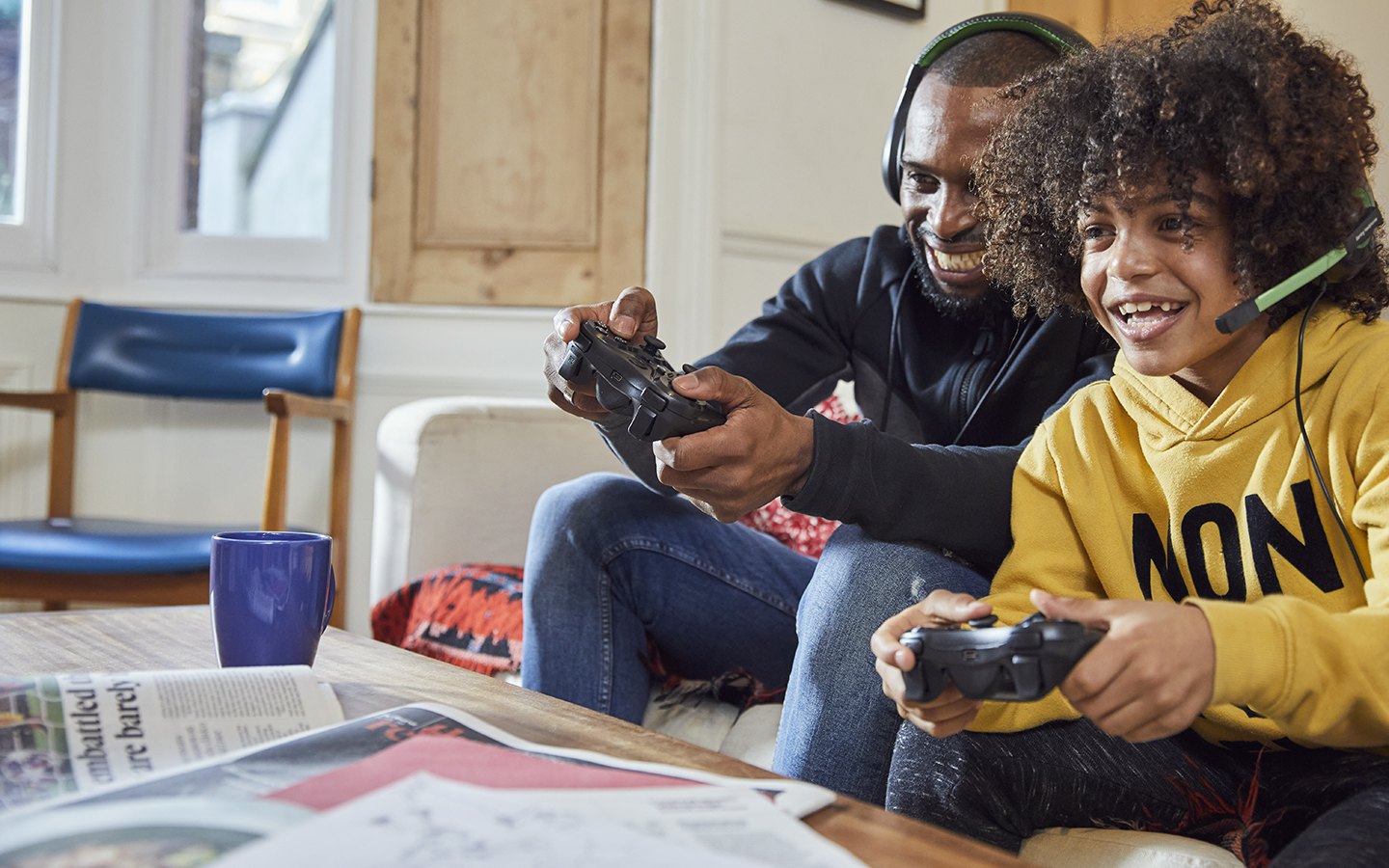 A parent/carer and their child playing a video game together in their living room.