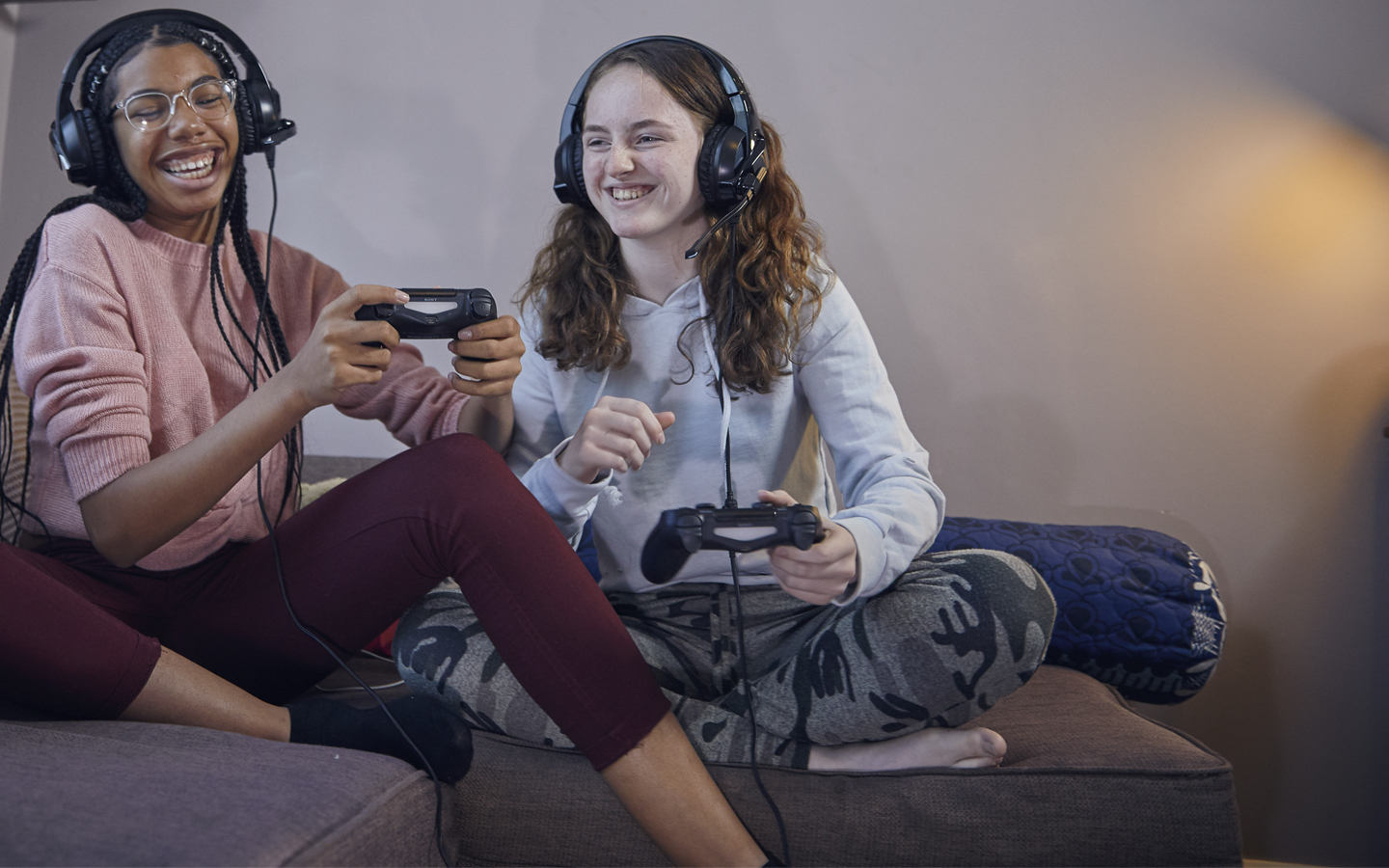 Two teenage girls playing on games consoles