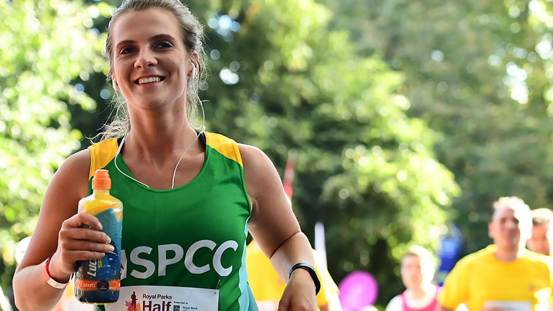 A Team NSPCC member running and smiling during the Royal Parks Half Marathon.
