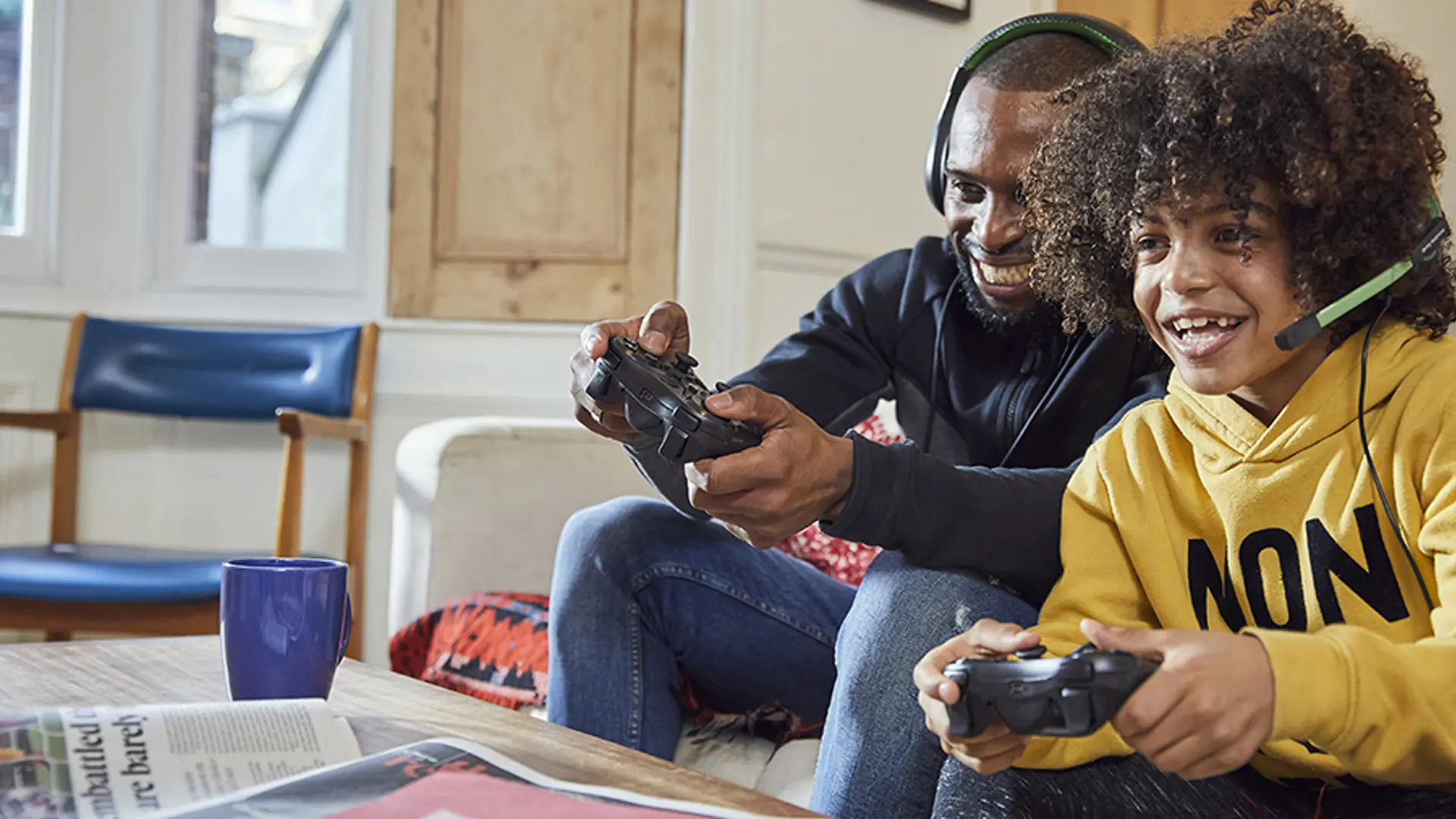 A parent/carer and their child playing a video game together in their living room.