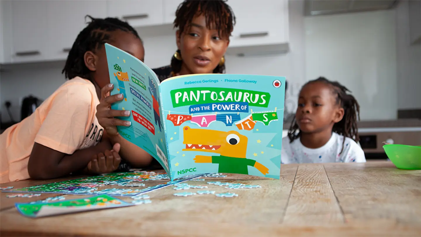 A mother and two young children reading the Talk PANTS book together.