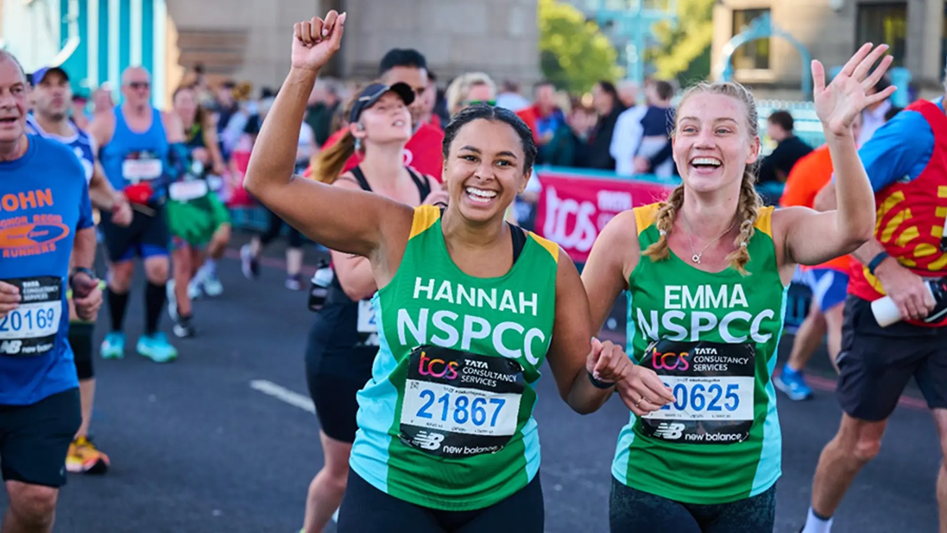 Two Team NSPCC members smiling while running in an event.